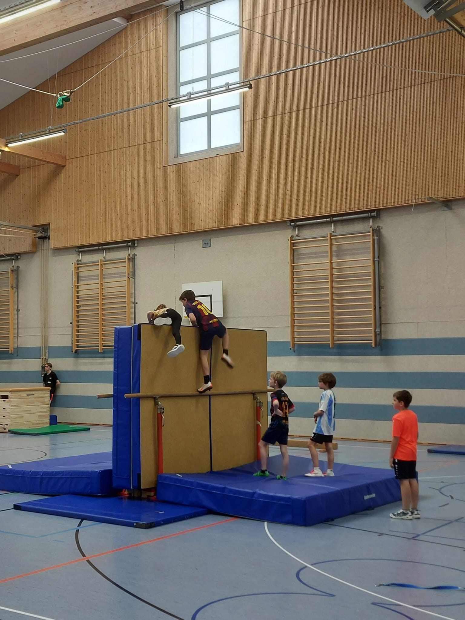 Kinder klettern über eine Hindernis-Mauer